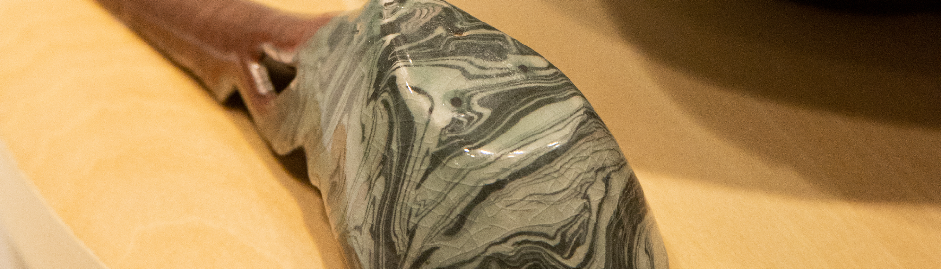 detalhe de colher de cerâmica marmorizada com cor verde sobre mesa branca