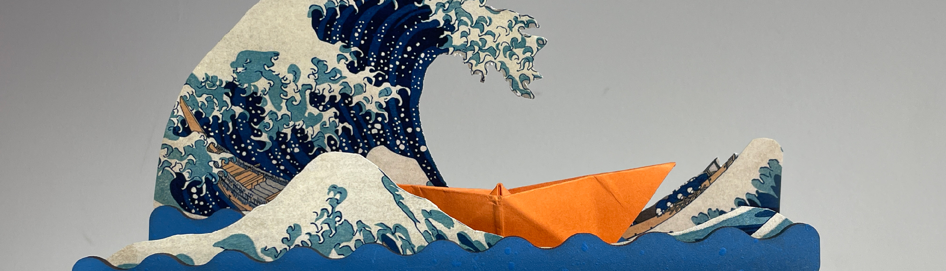 Detalhe de autômato feito na oficina infantil do Educativo da JHSP. O brinquedo mostra ondas azuis com um barco de papel laranja navegando no oceano.
