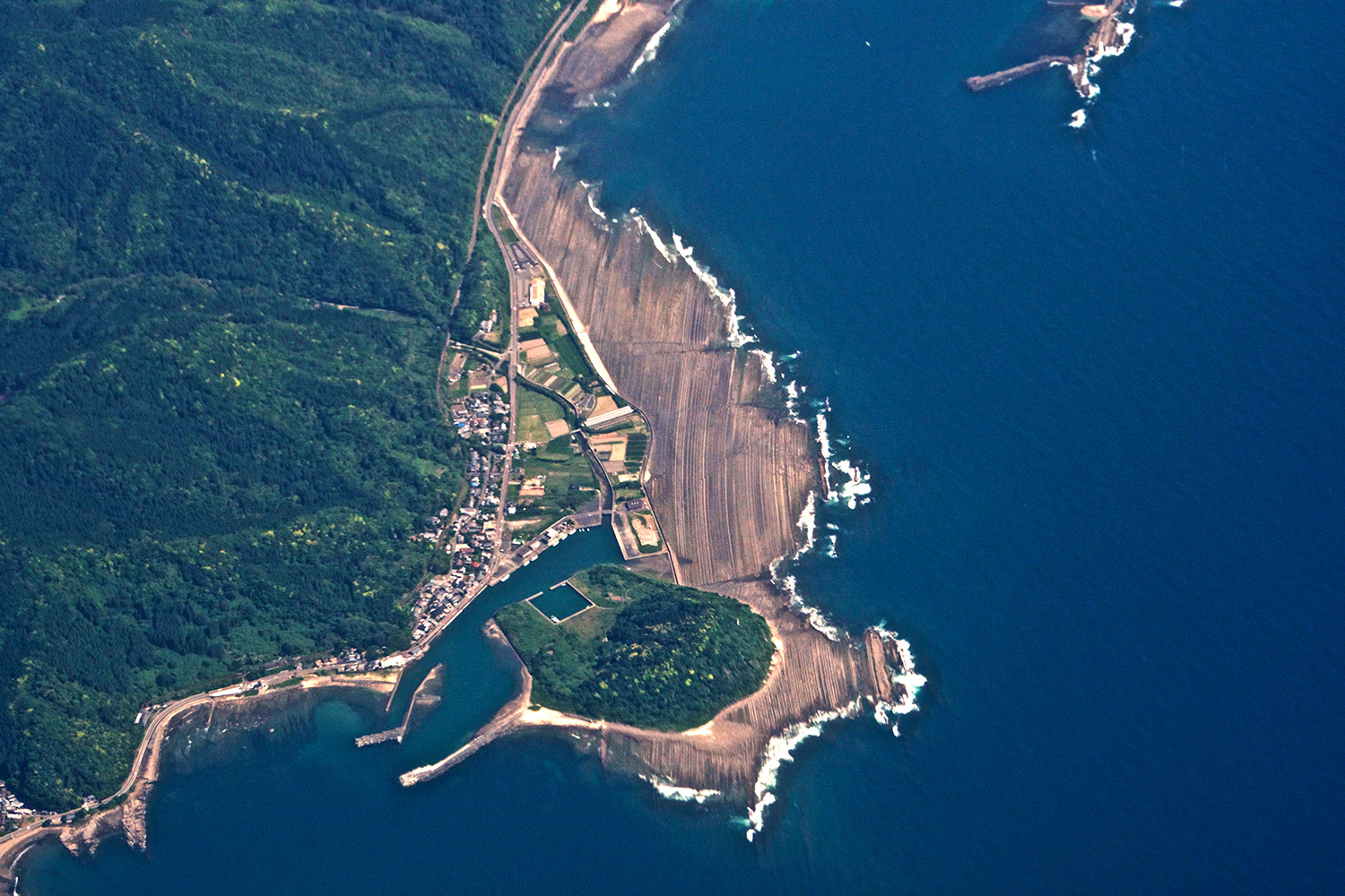 Vista aérea de costa banhada por mar azul escuro.