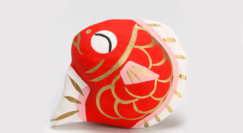 Imagem de um amuleto tradicional japonês de um peixe em cor vermelha e dourada.